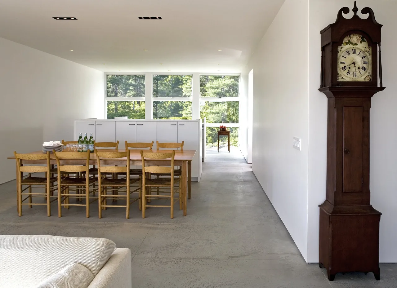 Dining area with wooden furniture and concrete floor in Punkinville House by bruce norelius studio.