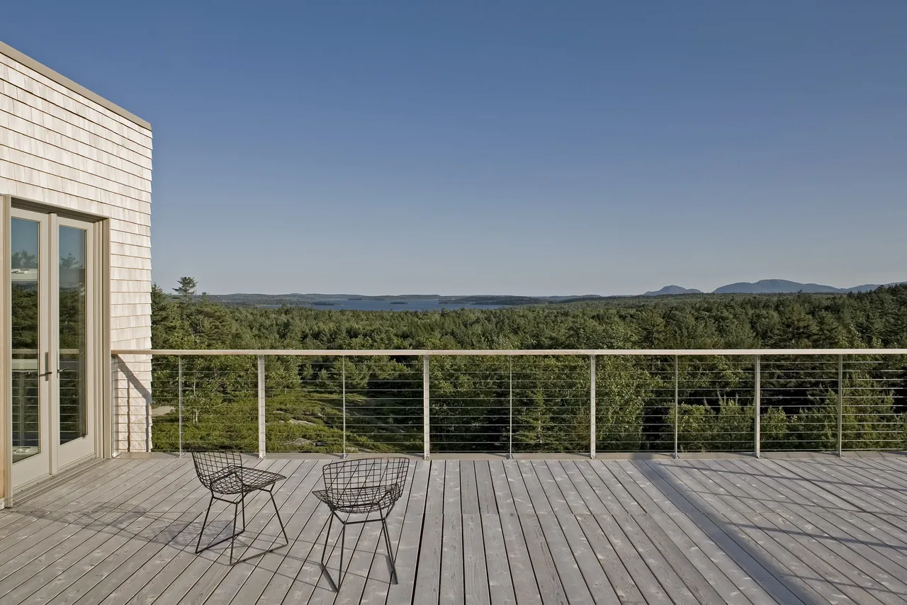 The rooftop deck of Punkinville House features wooden decking and a cable railing system with expansive views of forested land and distant mountains.