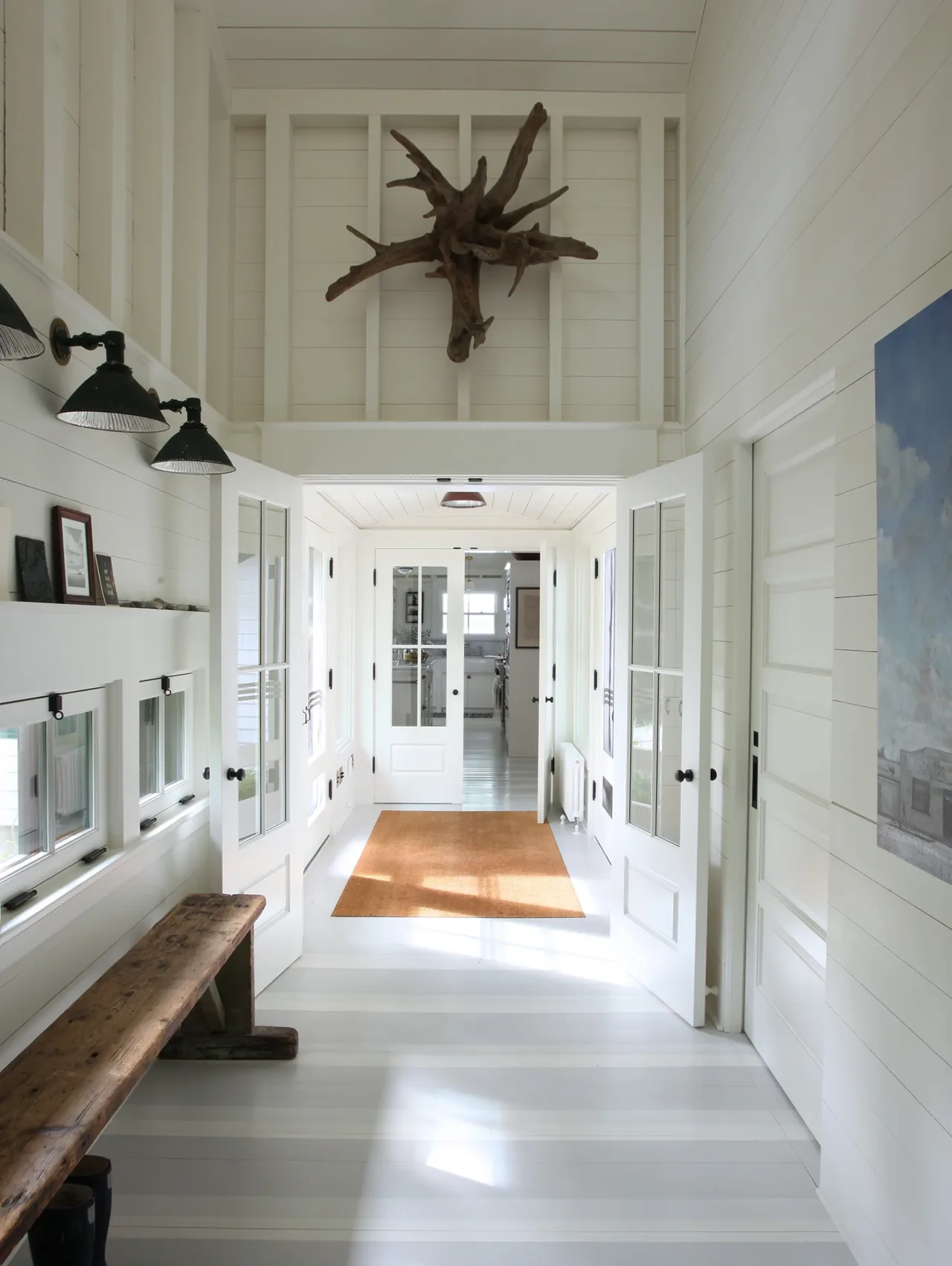 Hallway with white shiplap walls, wood bench, and pendant lights at Lakeside Camp by bruce norelius studio.