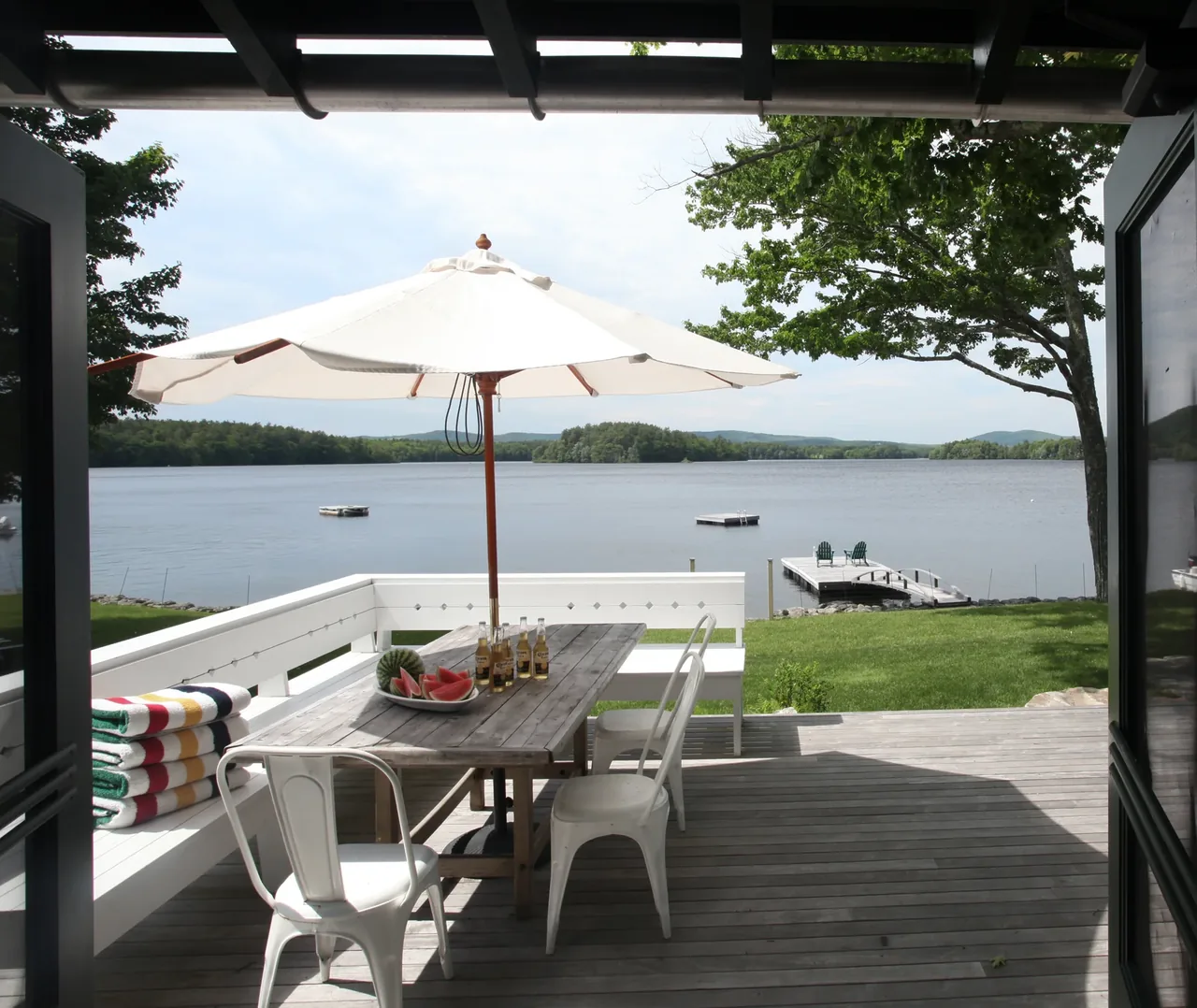 Lakeside deck with outdoor dining table and umbrella facing lake views in the Lakeside Camp project.
