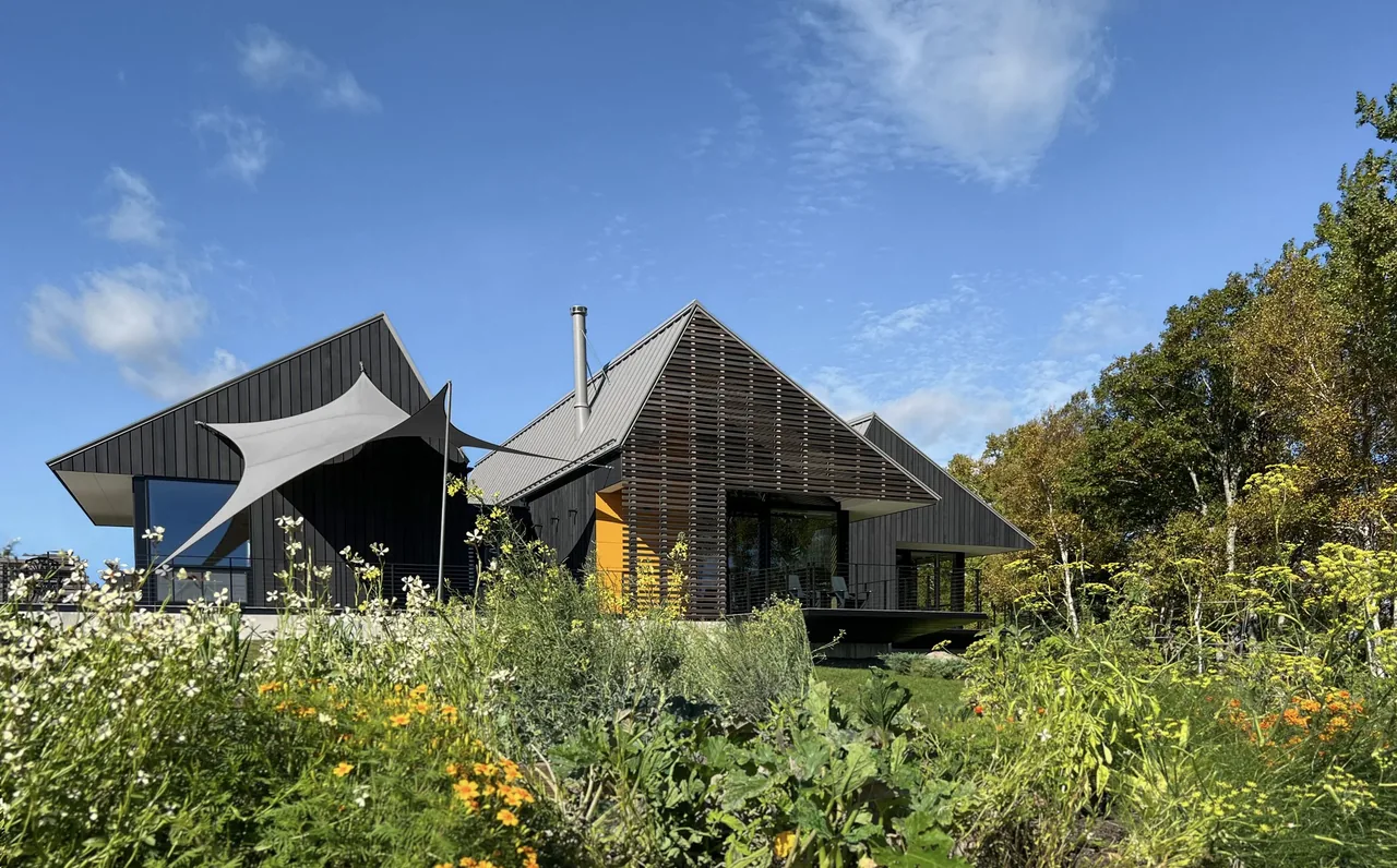 Howe Hill Crows Nest features three gabled volumes on a sloped site with wood siding and outdoor living spaces.