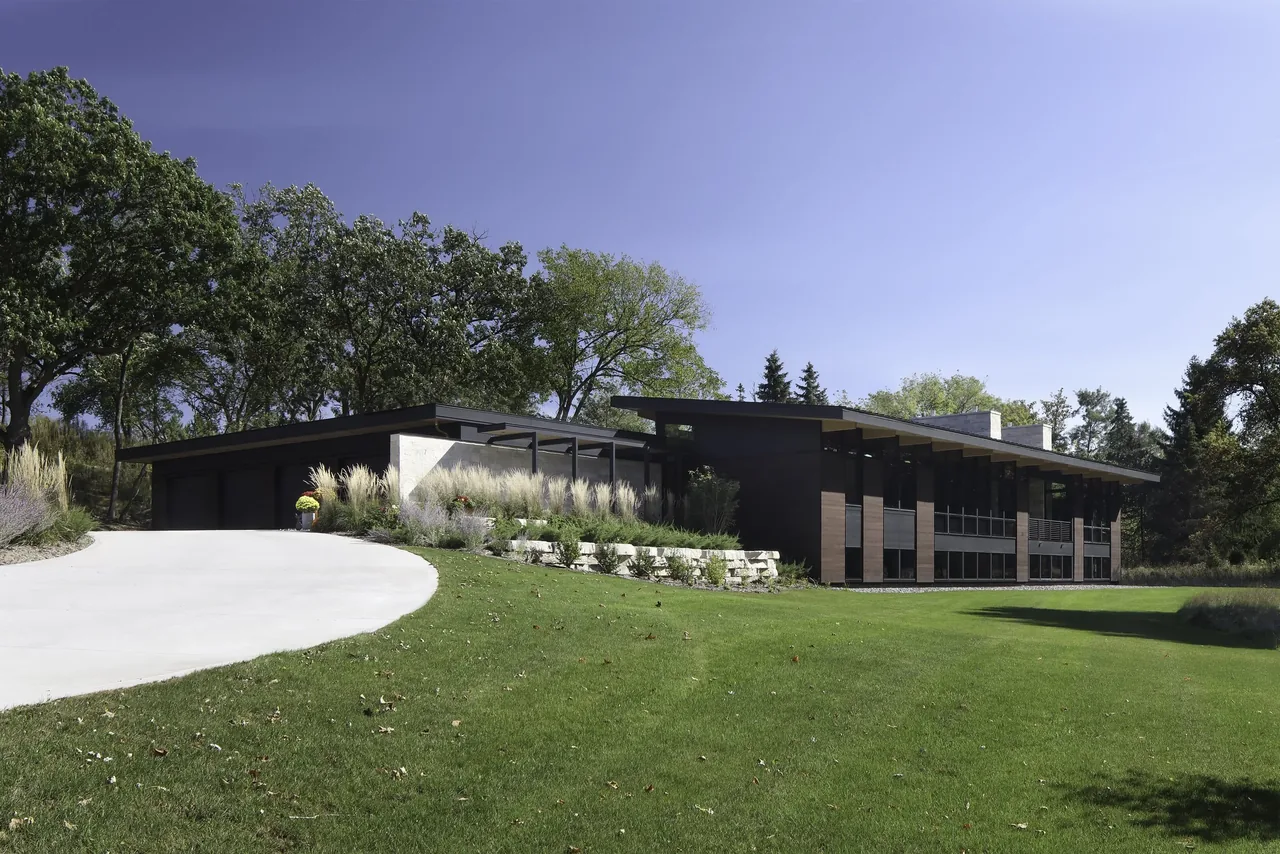 Art & Music House features a modern, low-pitched roofline with stone terrace walls blending into a natural landscape.