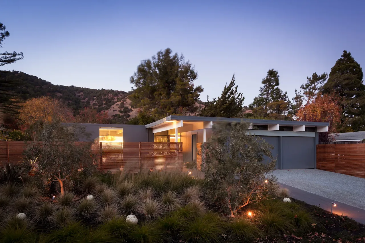 Appleberry Drive Residence by Building Lab features a flat roof and wooden privacy fence in a natural setting.