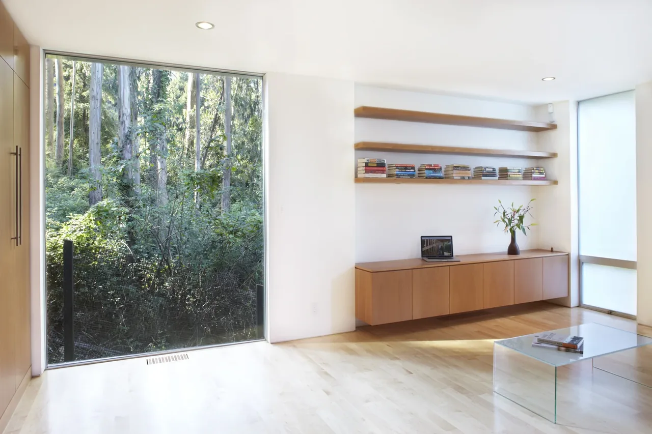 Living room with floor-to-ceiling glazing, a floating cabinet, and clear glass coffee table in a modern style.