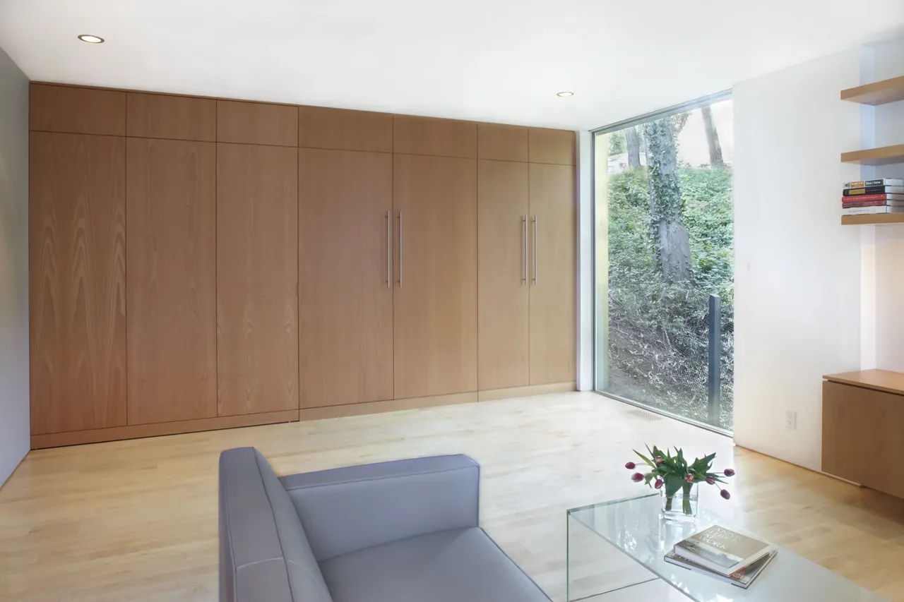 Living room with wood panel cabinets and a floor-to-ceiling window overlooking a garden area.