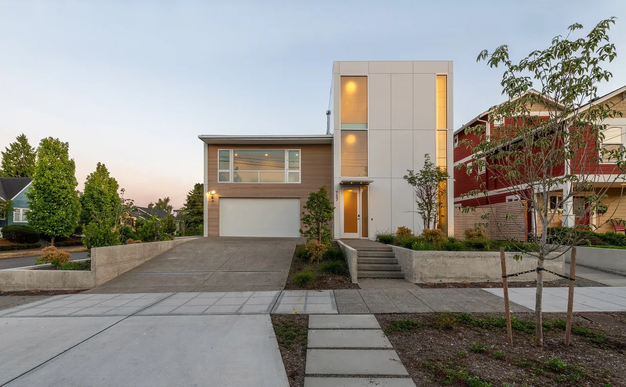 Greenwood Residence front view featuring modern design with concrete steps and landscaped yard.