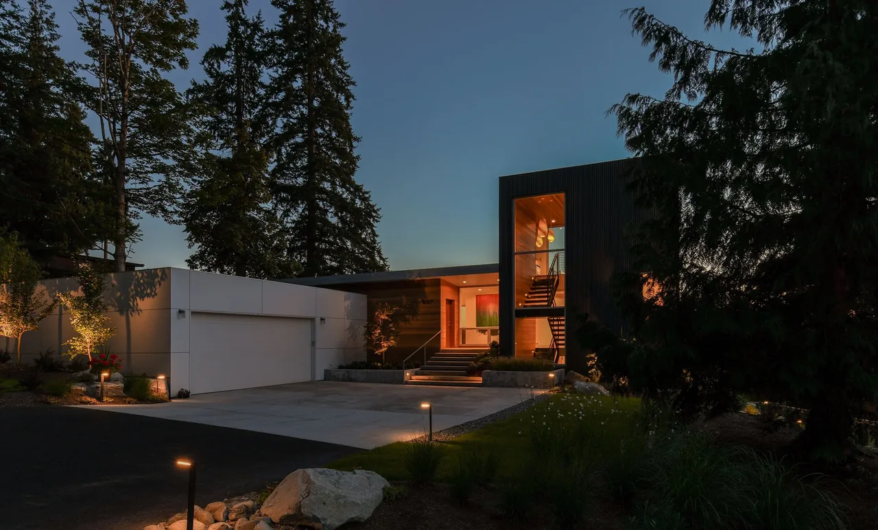 Sammamish Residence features vertical windows and illuminated concrete stairs at the entry, blending wood and metal materials.