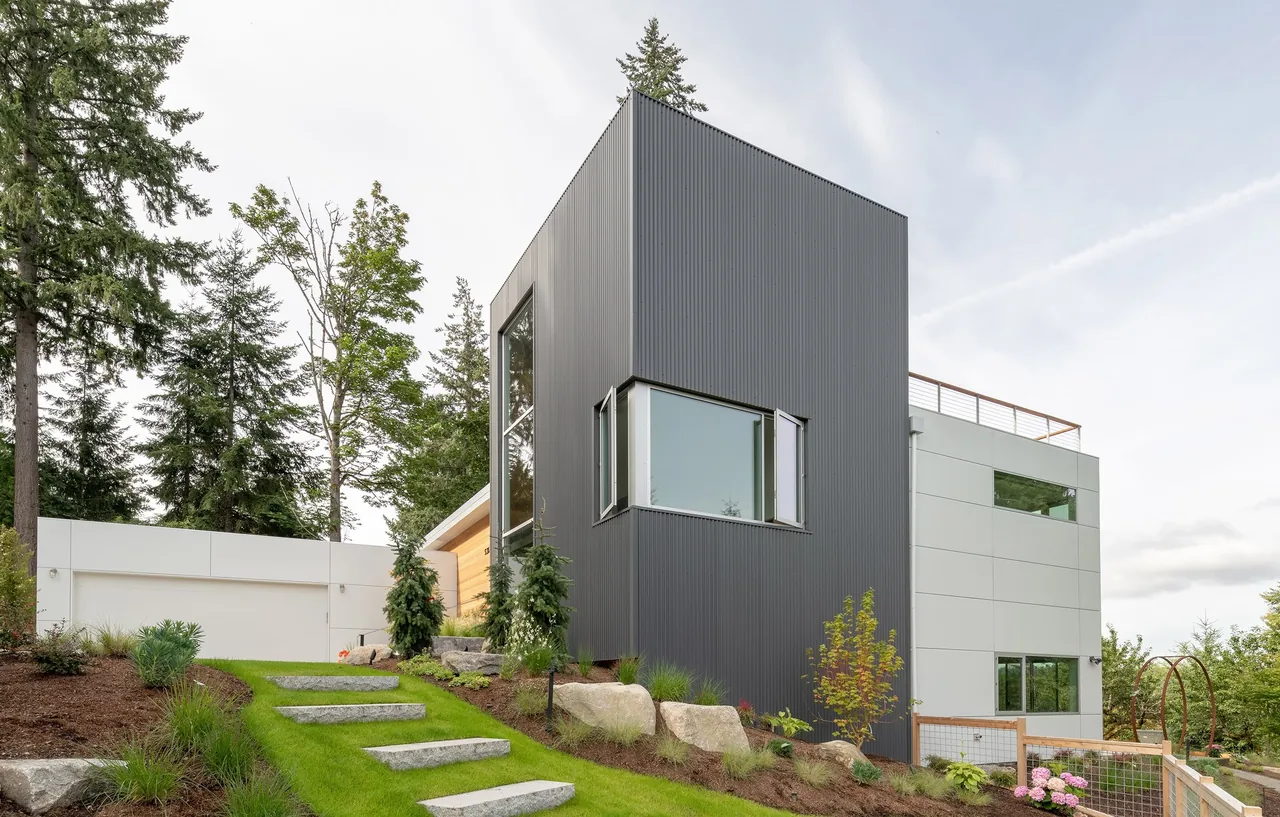 Sammamish Residence features dark metal siding and concrete stairs integrated into a landscaped slope near Seattle.