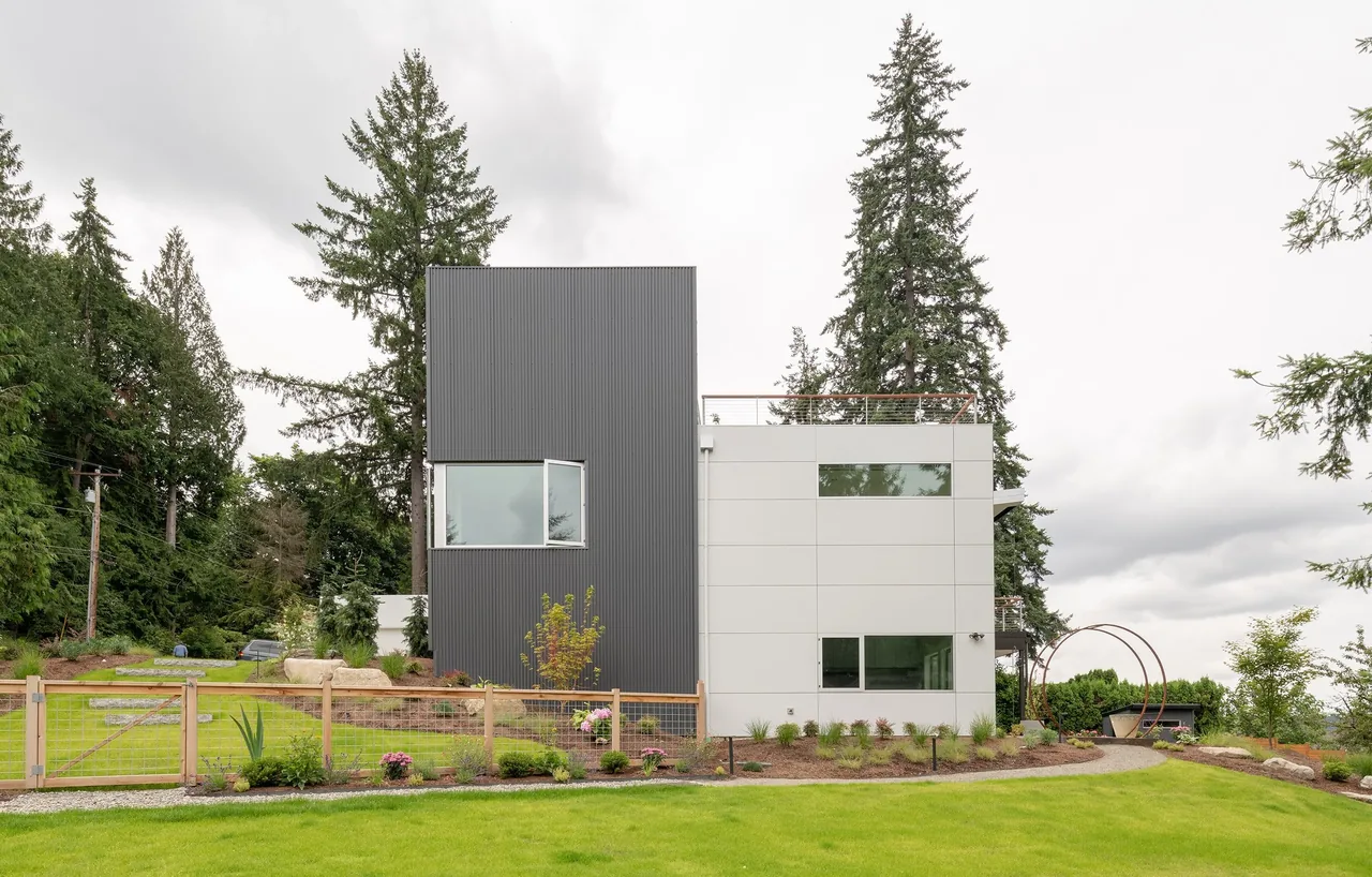 Sammamish Residence features vertical metal siding and light panel siding with large rectangular windows.