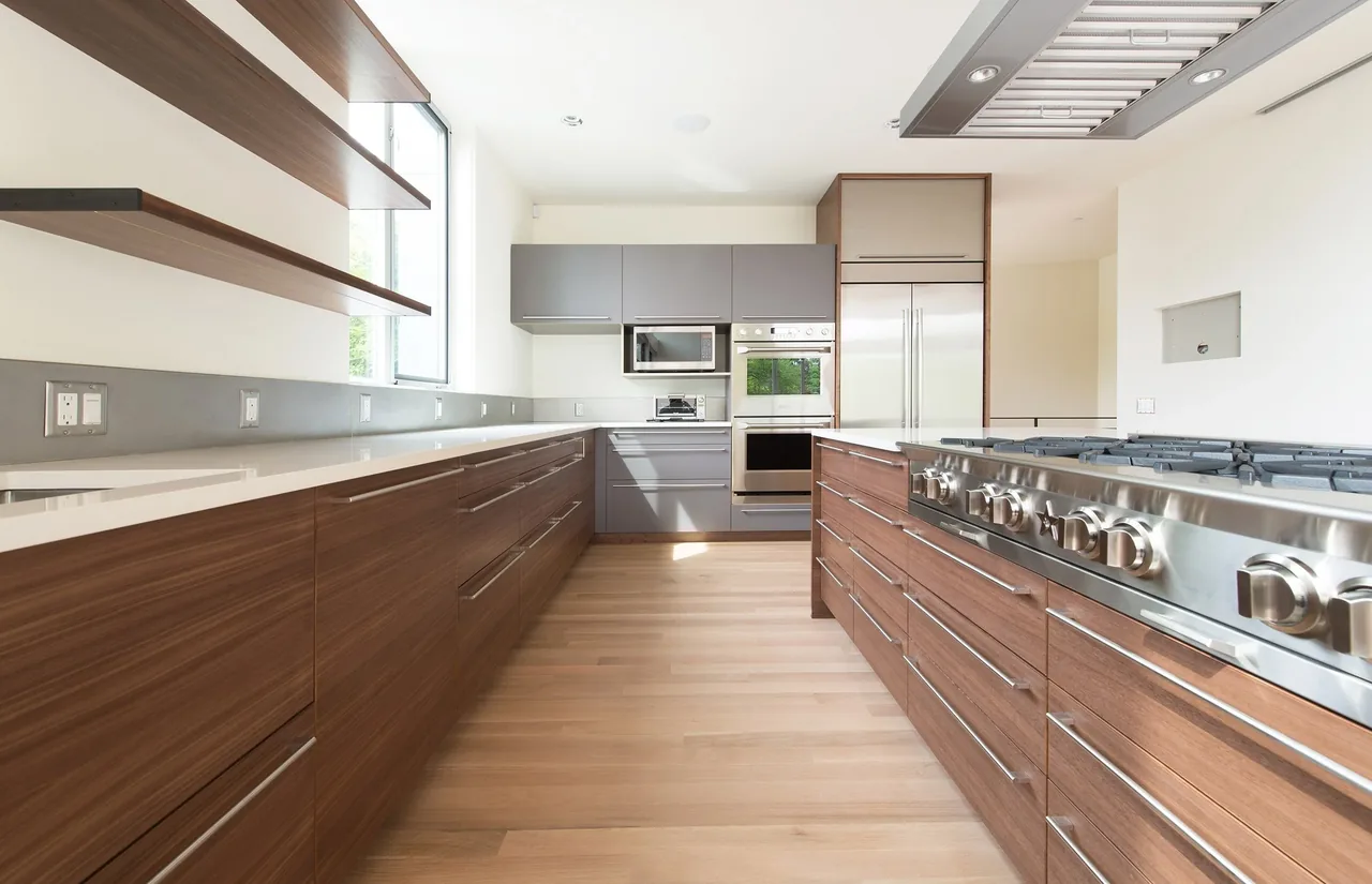 Mercer Island Residence kitchen by Build LLC features wood cabinetry, stainless appliances, and floating shelves.