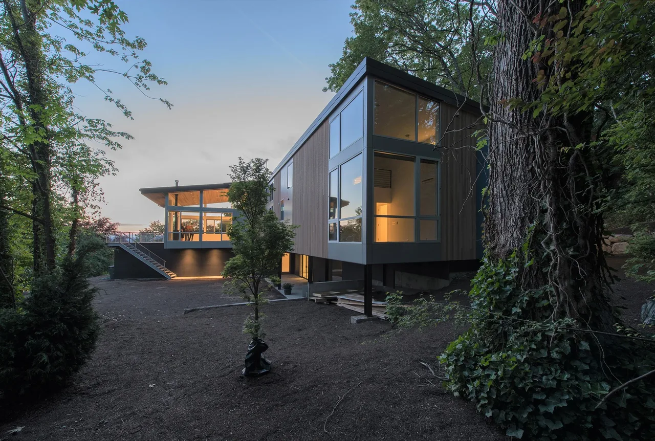 Mercer Island Residence by Build LLC features a light wood-paneled exterior with large glass windows and a cantilevered design.
