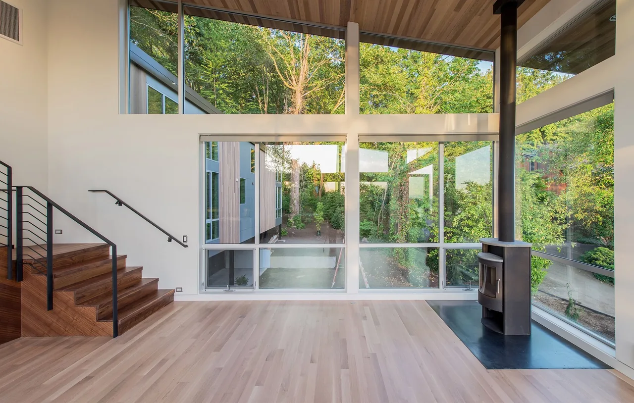 Living room of Mercer Island Residence features large windows and a black freestanding wood stove on a metal hearth.