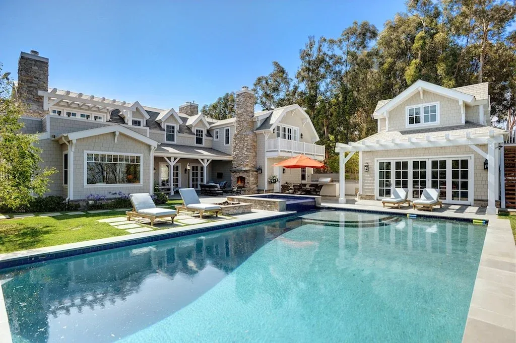 The Dume Drive Traditional house features a pool with adjacent lounge chairs and a pergola-covered patio area.