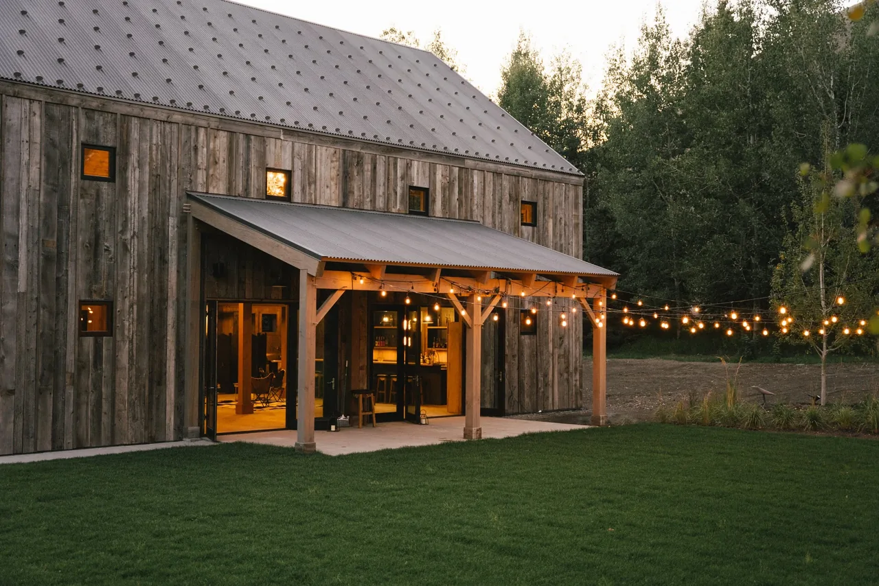 Riverside Retreat features weathered wood siding and a covered patio with hanging string lights in Los Angeles.