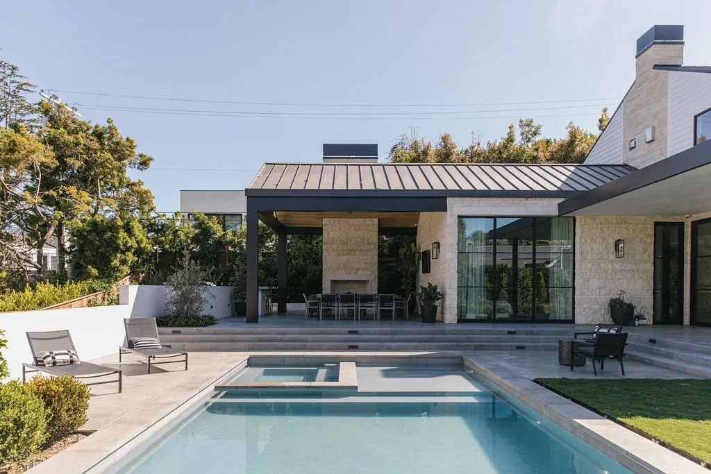 Malibu Modern features a poolside covered patio with outdoor seating and a landscaped lawn.