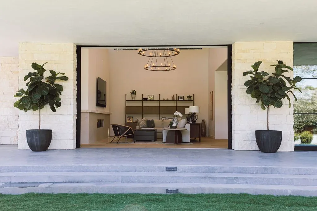 Living room with large open wall, light stone walls, and minimalist furnishings in the Malibu Modern residence by Burdge & Associates Architects.