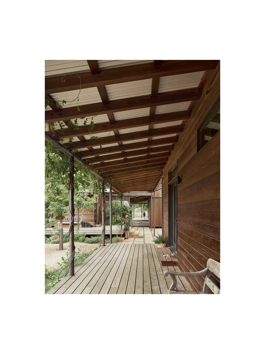 Wooden covered porch with slatted decking and dark wood siding at Roam Ranch project.