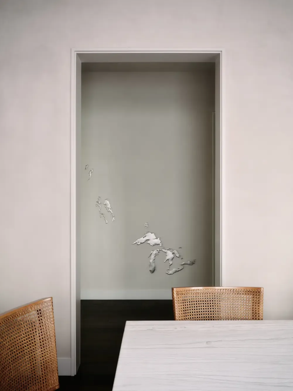 Minimalist interior with woven chairs framing a doorway in the Presidio Heights Residence by Butler Armsden Architects.
