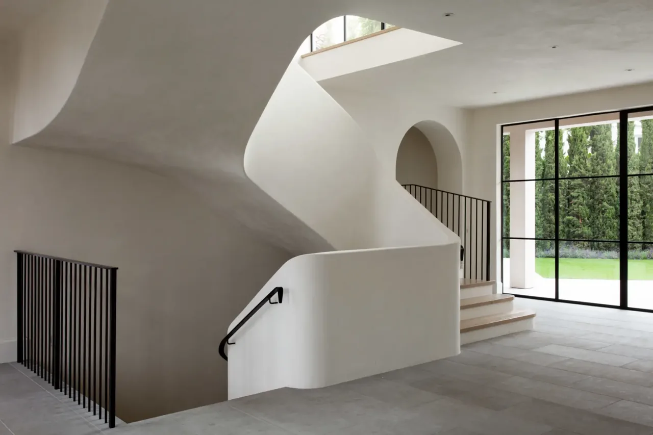The Sea Cliff Sculptural project features a smooth curved stairwell and black metal railings with floor-to-ceiling black-framed glazing.