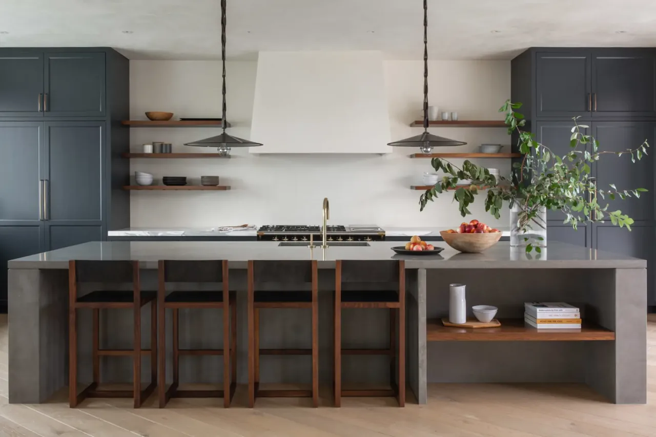 Sea Cliff Sculptural kitchen by Butler Armsden Architects features a gray island with wood stools and dark cabinets.