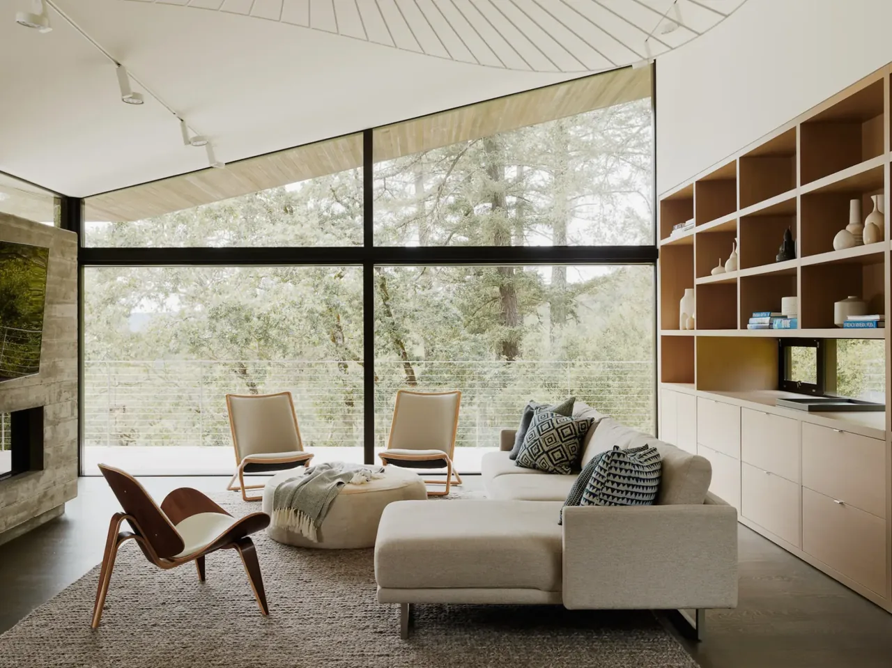 Living room features floor-to-ceiling black-framed windows and a built-in wood shelving wall at Valley of the Moon Retreat.