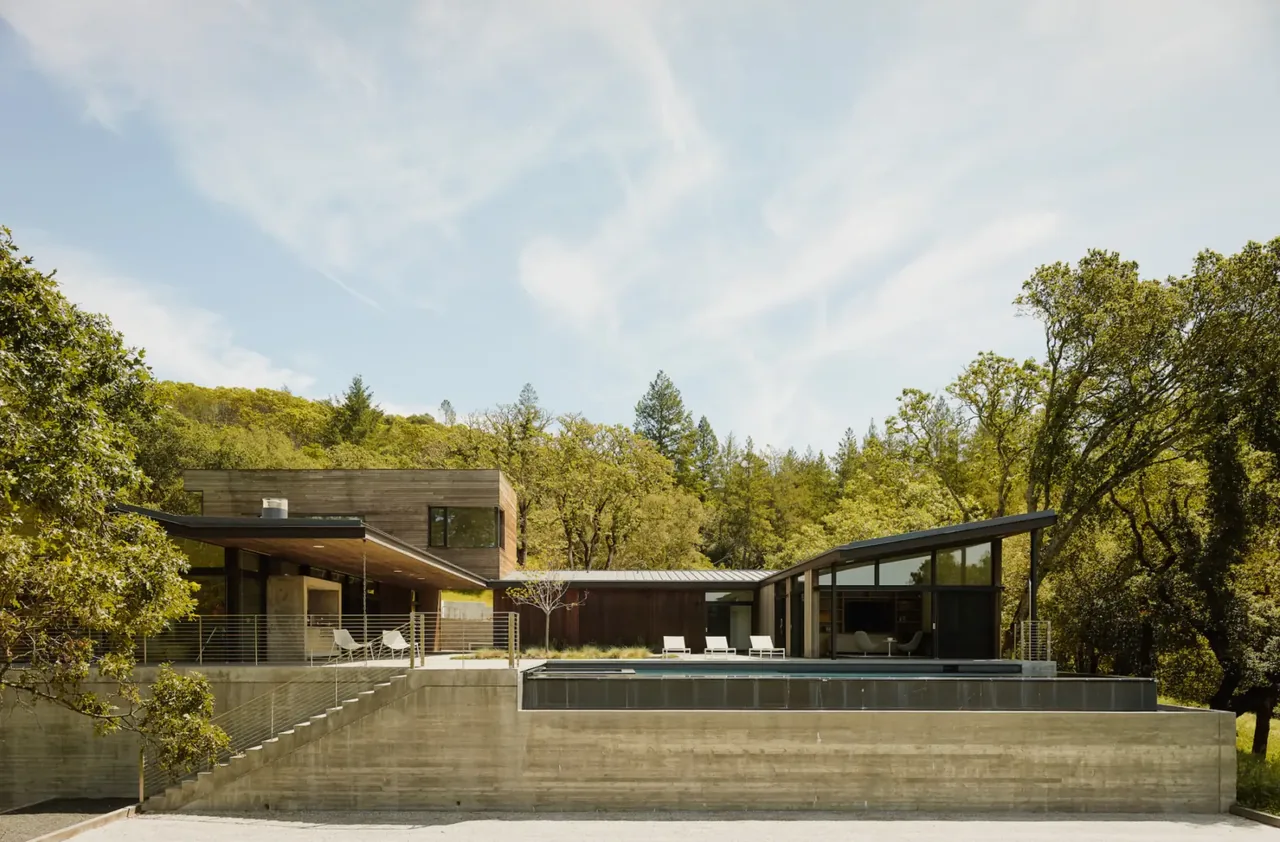 Valley of the Moon Retreat features a modern design with concrete base and floor-to-ceiling glazing, surrounded by trees.