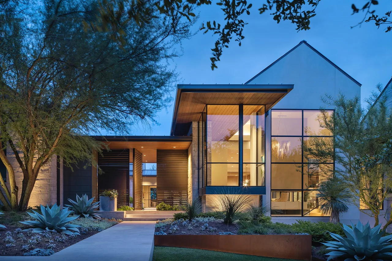 The Rollingwood Modern home features large floor-to-ceiling windows and slatted privacy screens with oxidized metal planters in the landscape.