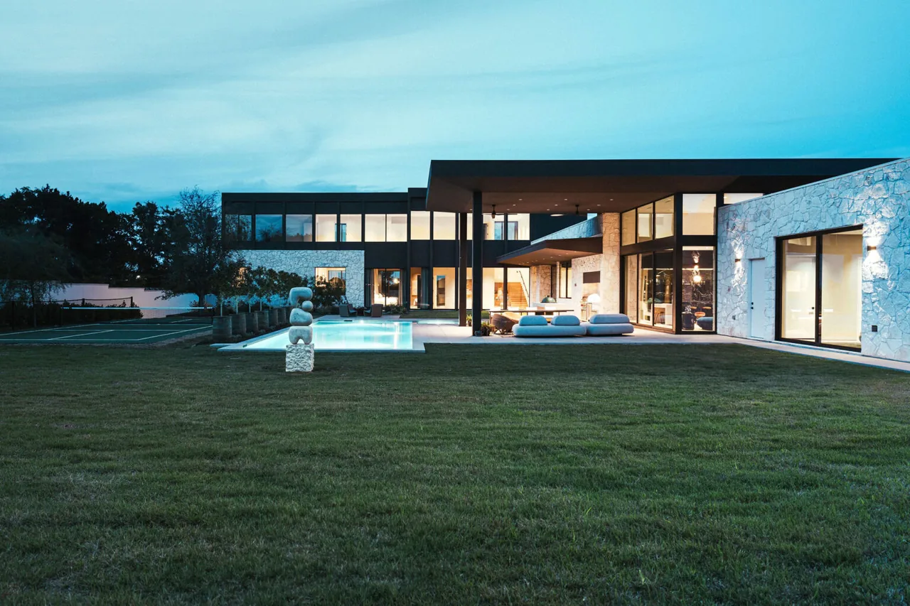 The FIVE Austin project features a contemporary home with expansive windows and stone cladding around a pool and patio area.
