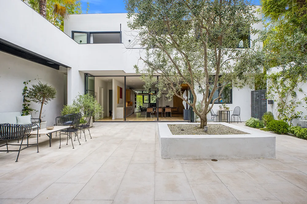 Exterior rear view of a modern house with an open courtyard and large sliding glass doors.