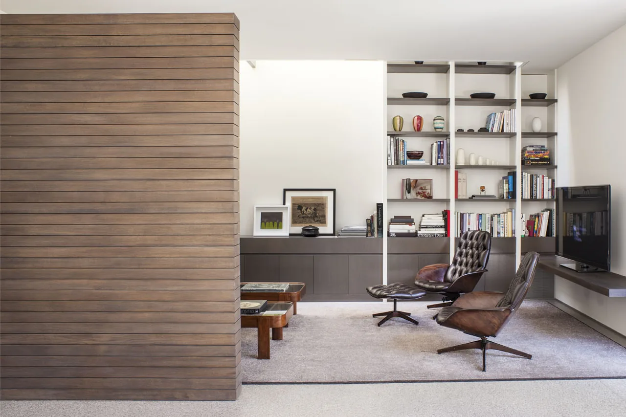 Living room features leather lounge chairs, built-in shelving, and a floating TV shelf in a contemporary style.