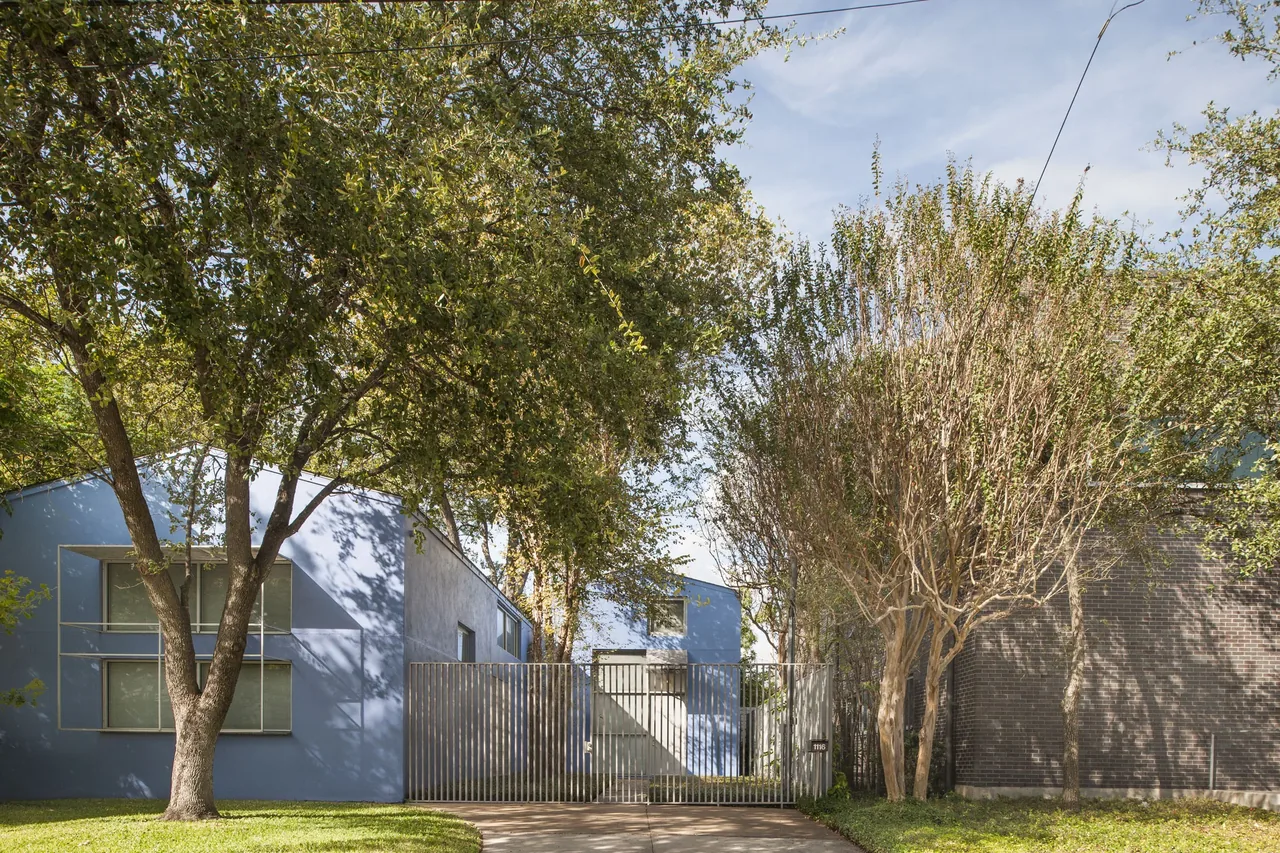 Crowley House features a low-profile modern design with blue exterior walls and a metal gate entry.