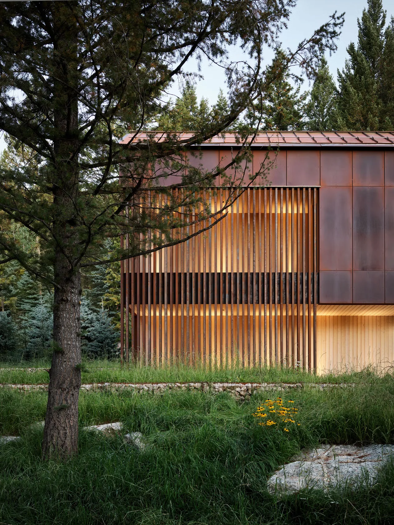 Exterior rear of Black Fox Ranch with vertical wood slat screening and rusted metal paneling by Carney Logan Burke Architects.