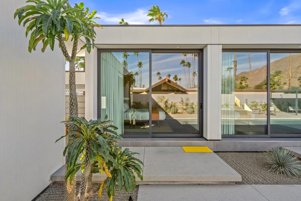 Exterior view of PALM SPRINGS project showing modern single-story house with floor-to-ceiling sliding glass doors and desert landscaping.