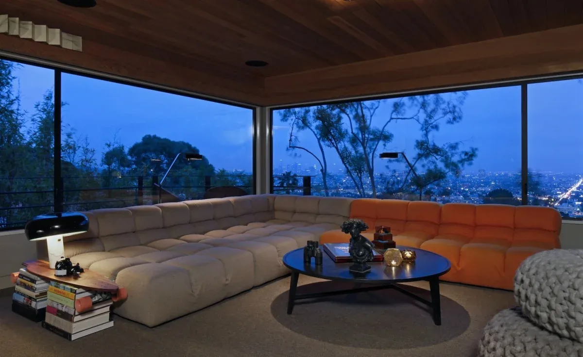 Living room at the Live Oak project featuring a sectional sofa and floor-to-ceiling windows with city views.
