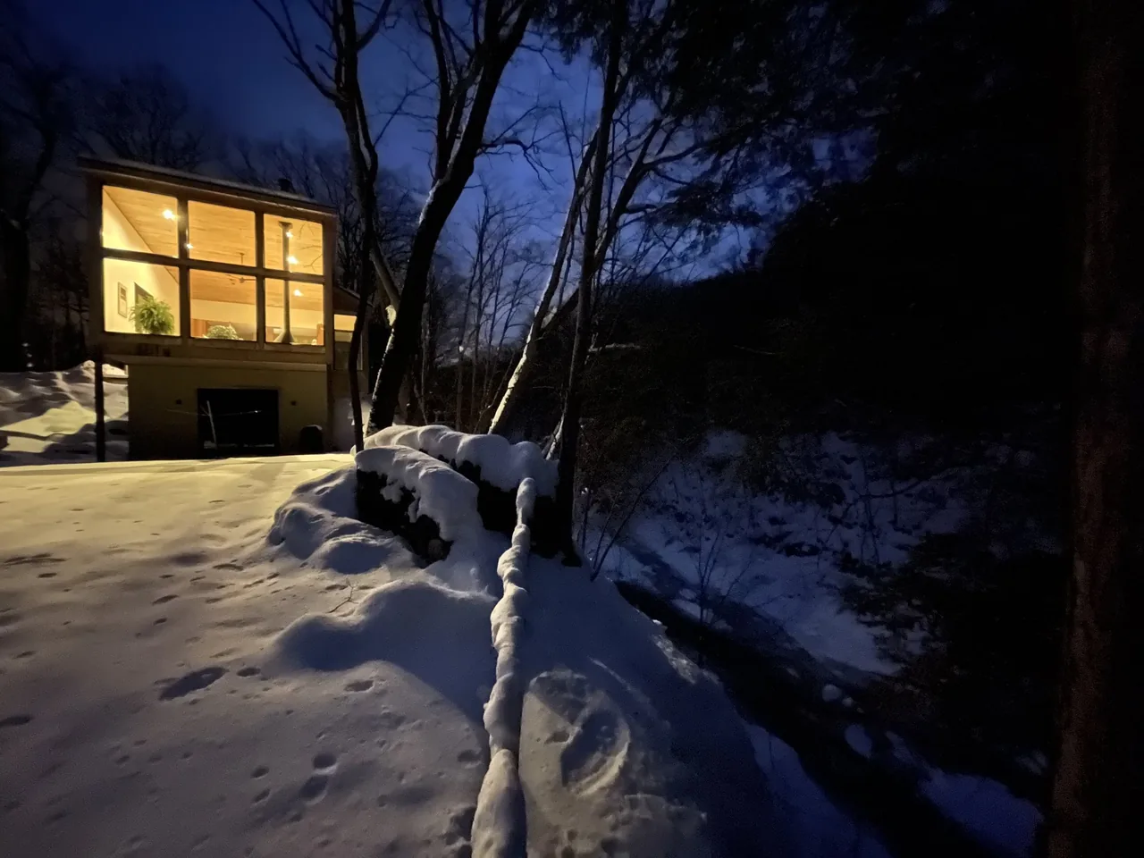 Canadaway House features large illuminated windows and a wood ceiling visible in the evening snow setting.