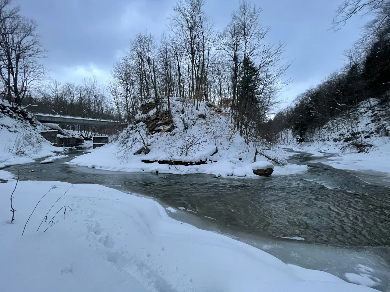Natural winter riverscape near Canadaway House showing snow-covered banks and leafless trees.