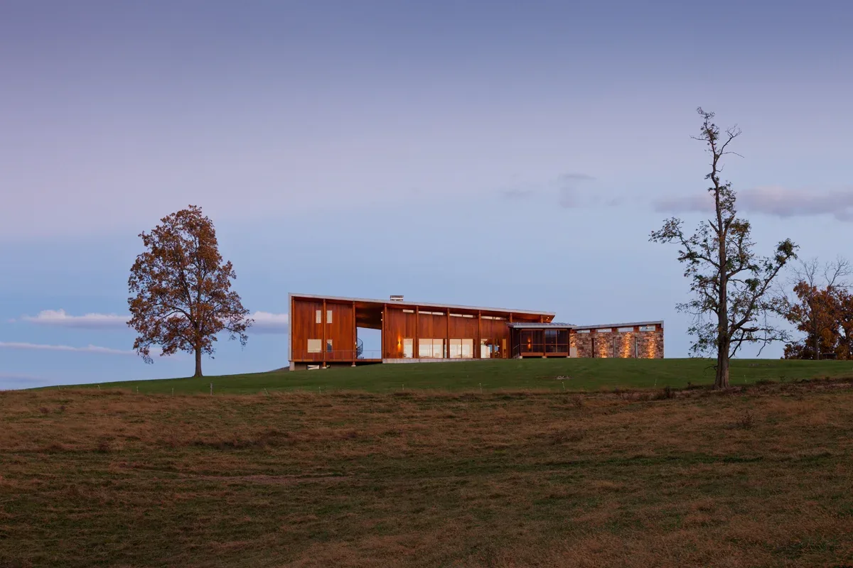 Elk Run Ridge features a modern home with wood siding and stone accents on a rural landscape.