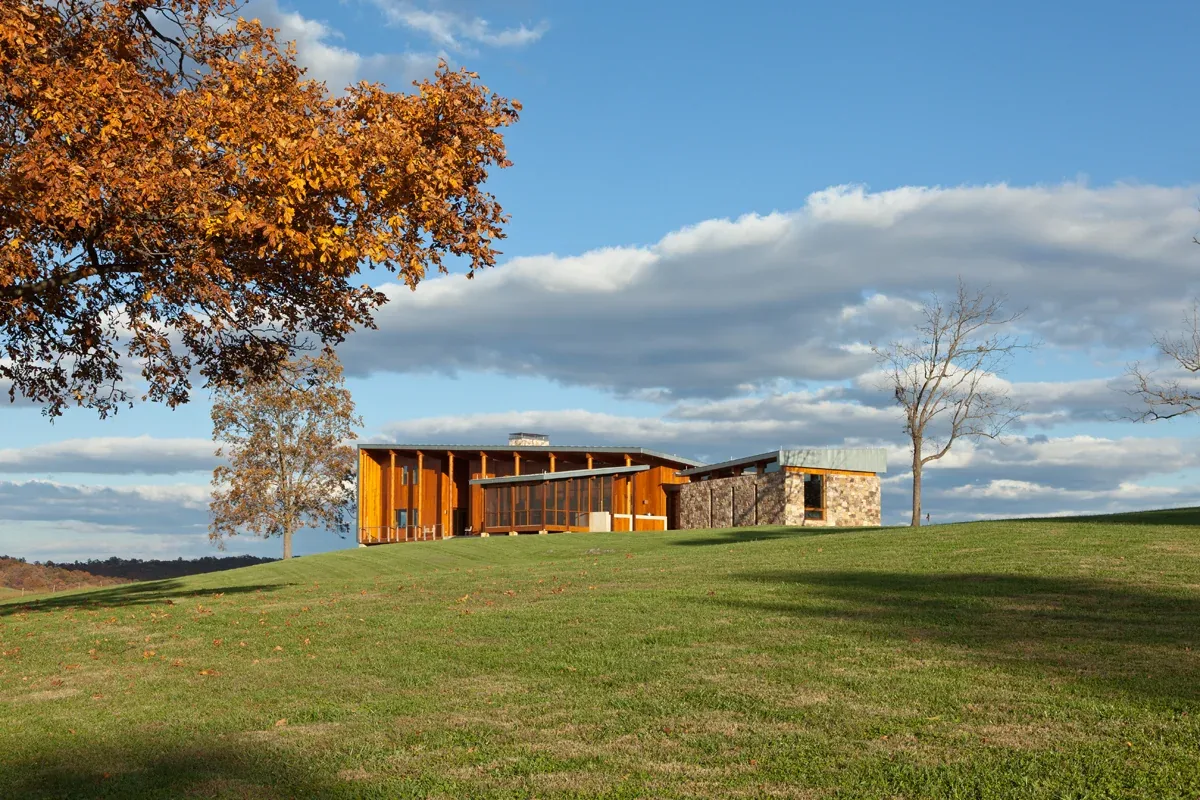 Elk Run Ridge features sloped roofs on a modern hilltop home with mixed wood and stone exterior finished by Carter + Burton.