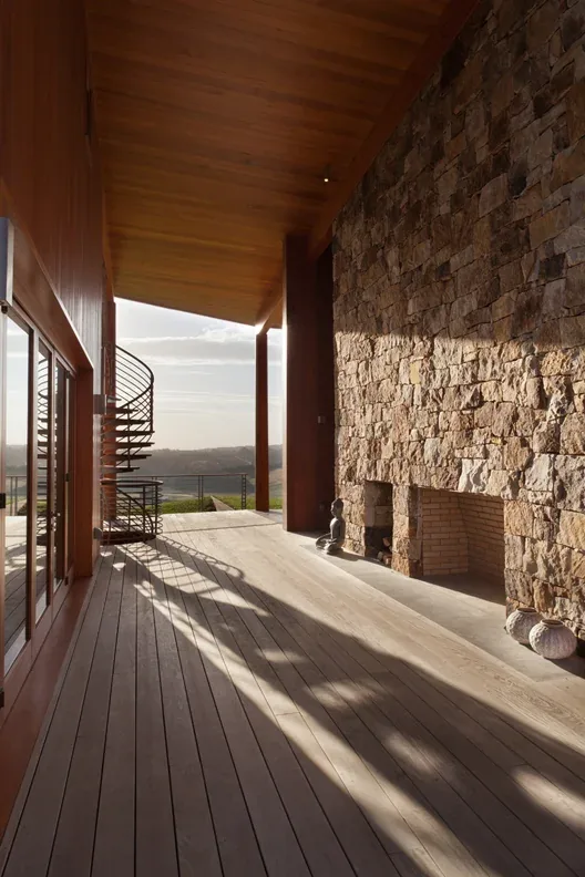 Elk Run Ridge covered patio features a large stone fireplace and a spiral staircase with wood ceiling and decking.