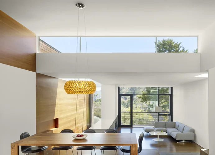 The Hill House interior features a modern, light-filled living and dining space with clerestory windows and black window frames.