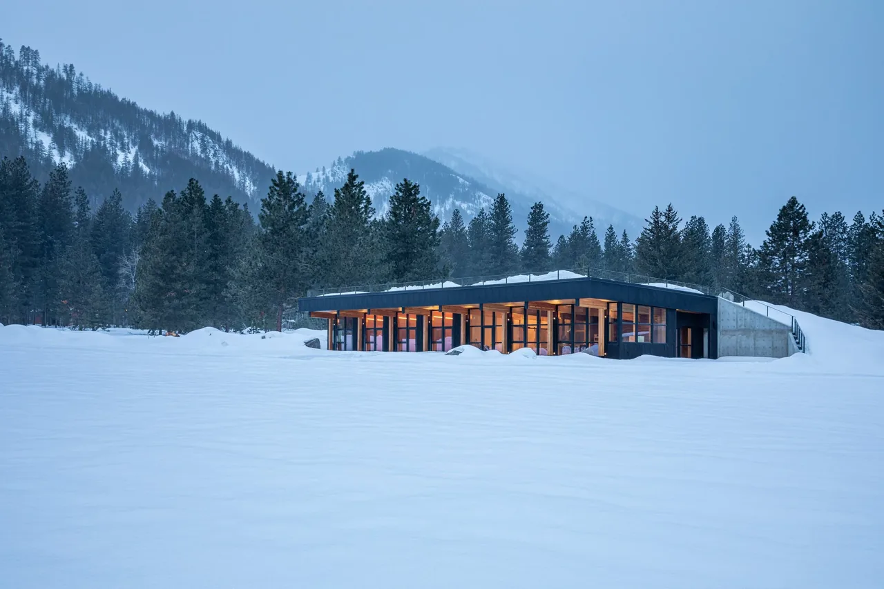 Berm house by CAST architecture is integrated into snowy landscape with floor-to-ceiling glazing and a flat roof.