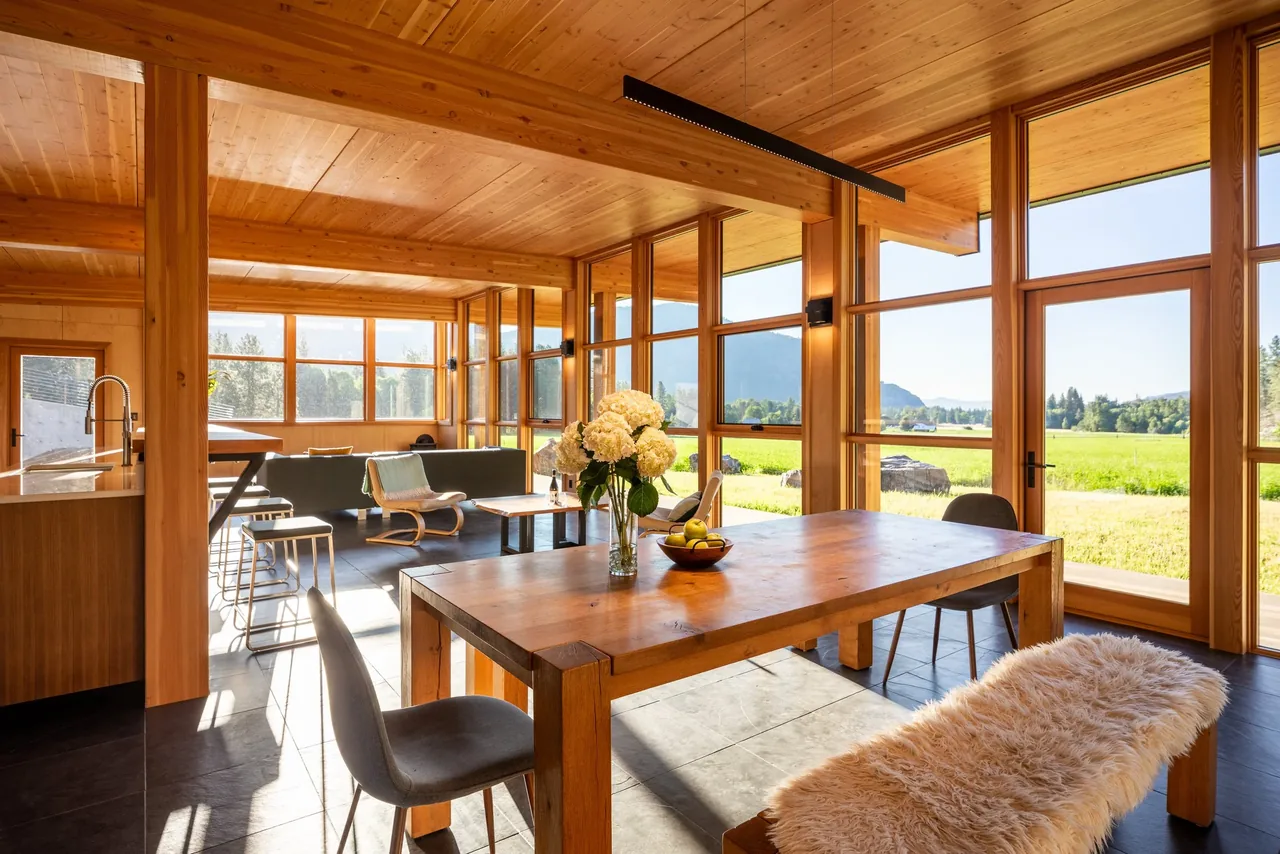 Dining and living area of Berm house designed by CAST architecture, featuring wood interiors and mountain views.