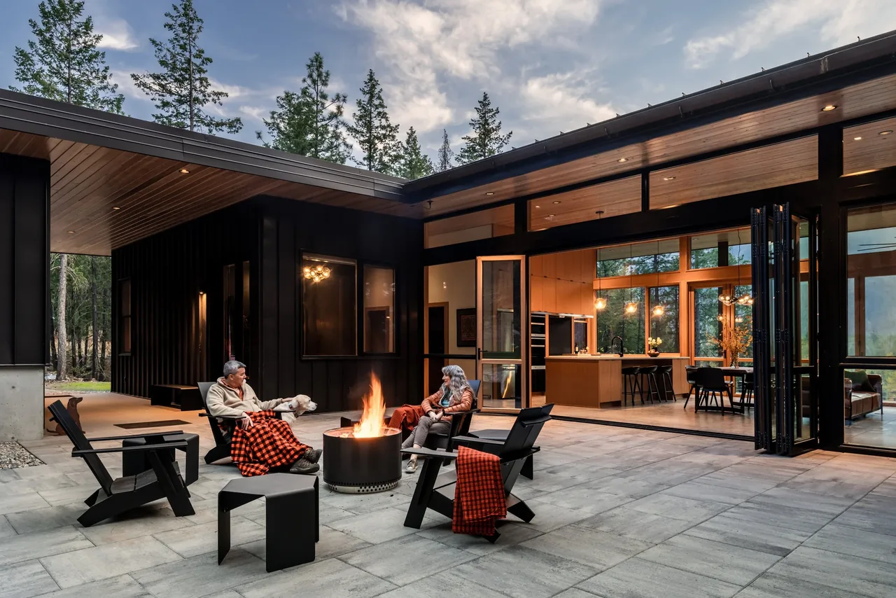 The outdoor patio with a fire pit opens directly to the interior kitchen and dining areas through folding glass doors.