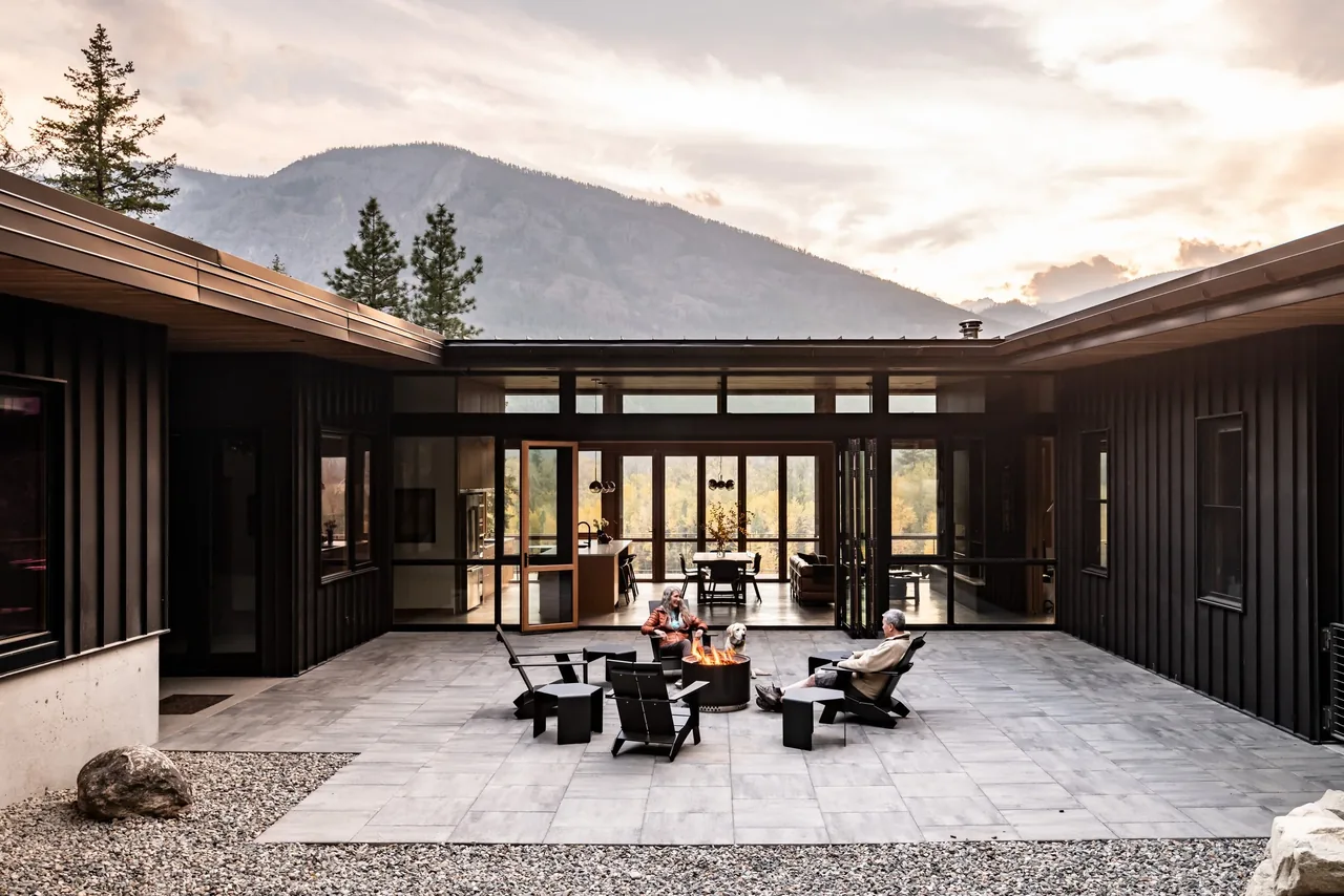 Outdoor living courtyard features a central fire pit surrounded by chairs and large glass doors opening to the interior.