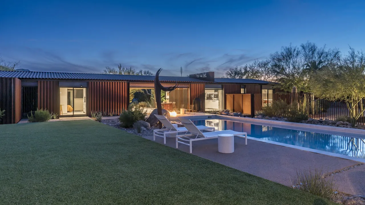 Backyard of 4018 casita features a rectangular pool and desert landscaping at dusk.