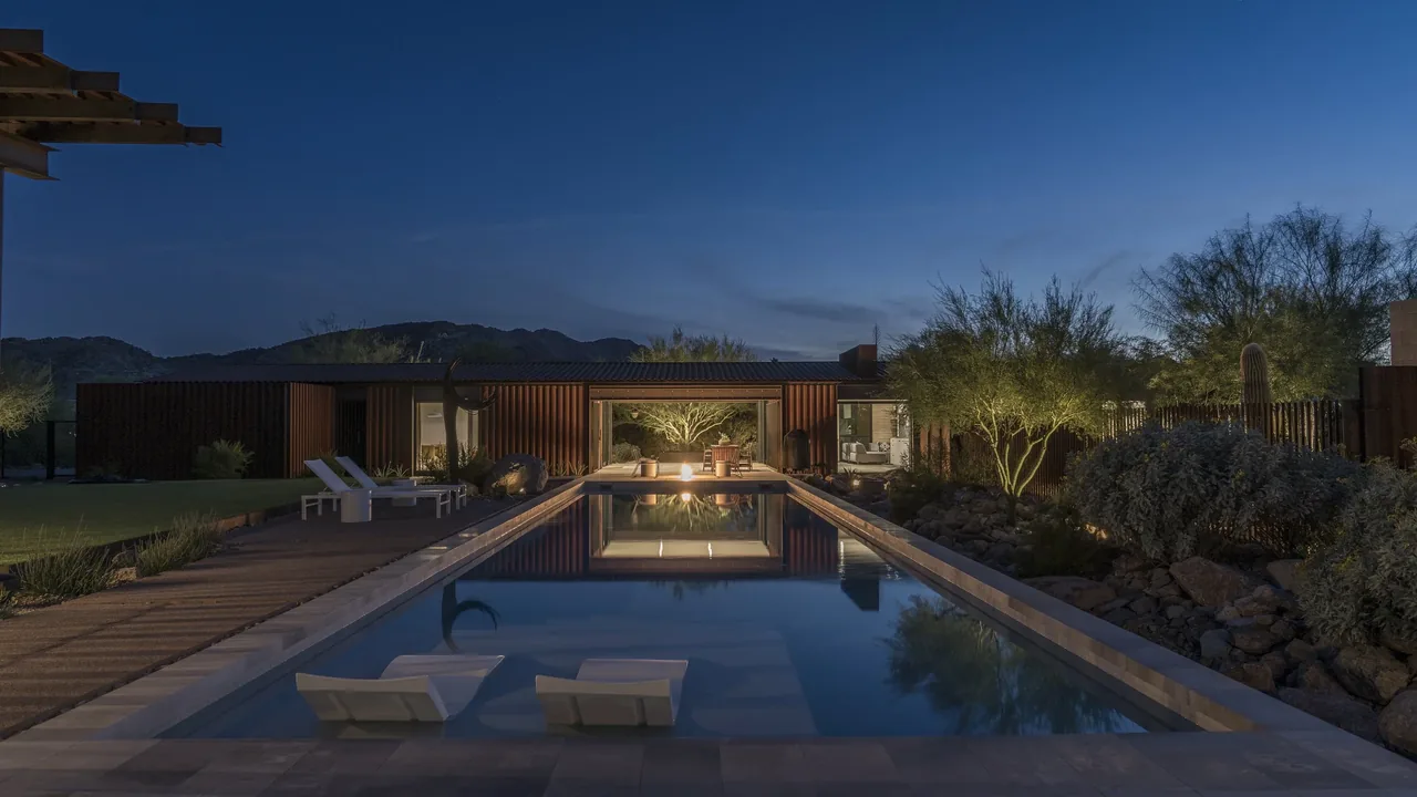 The 4018 casita features a pool with loungers and an illuminated modern exterior at dusk.