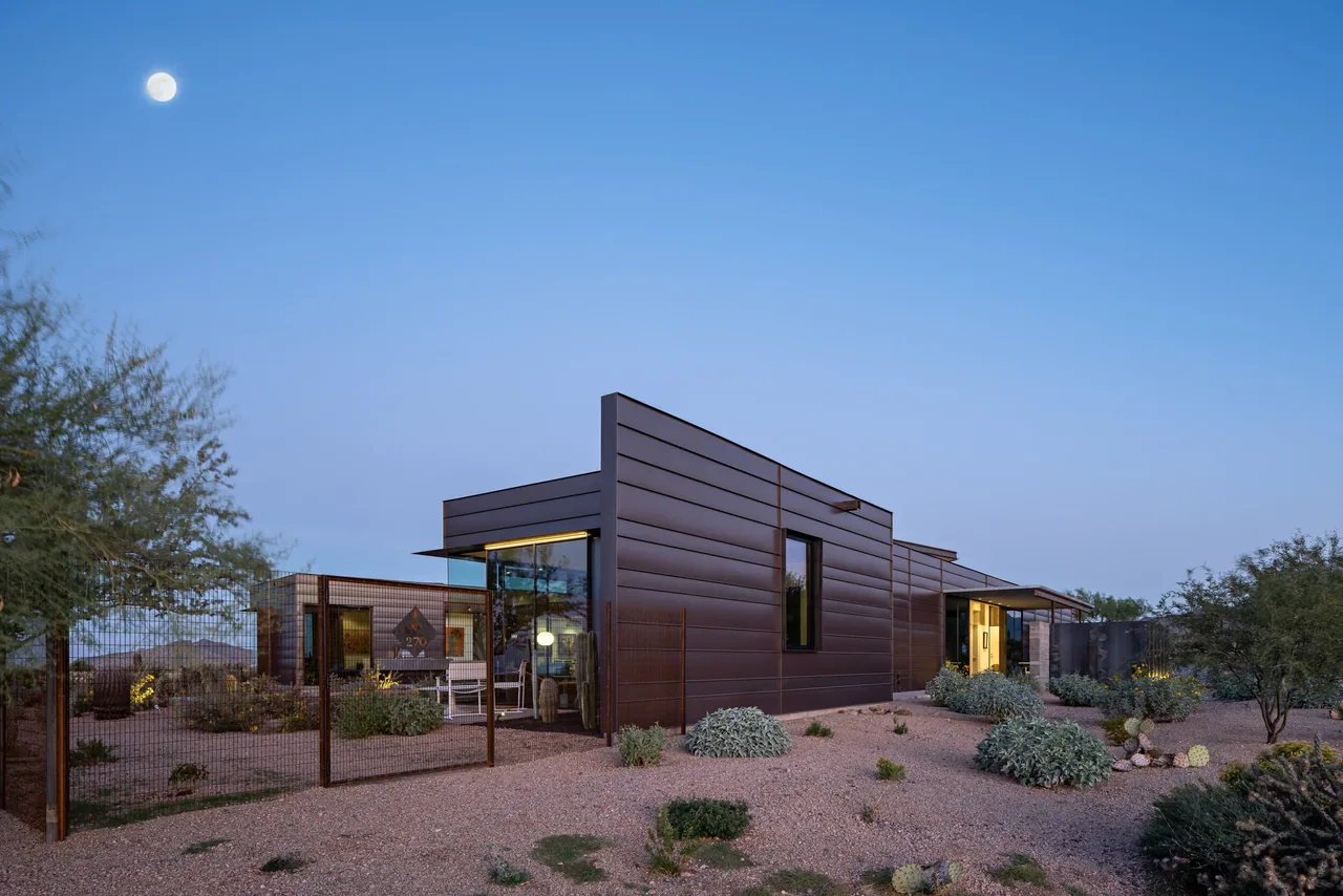The Balaschak project features horizontal dark metal siding in a modern design with large windows in a desert landscape.