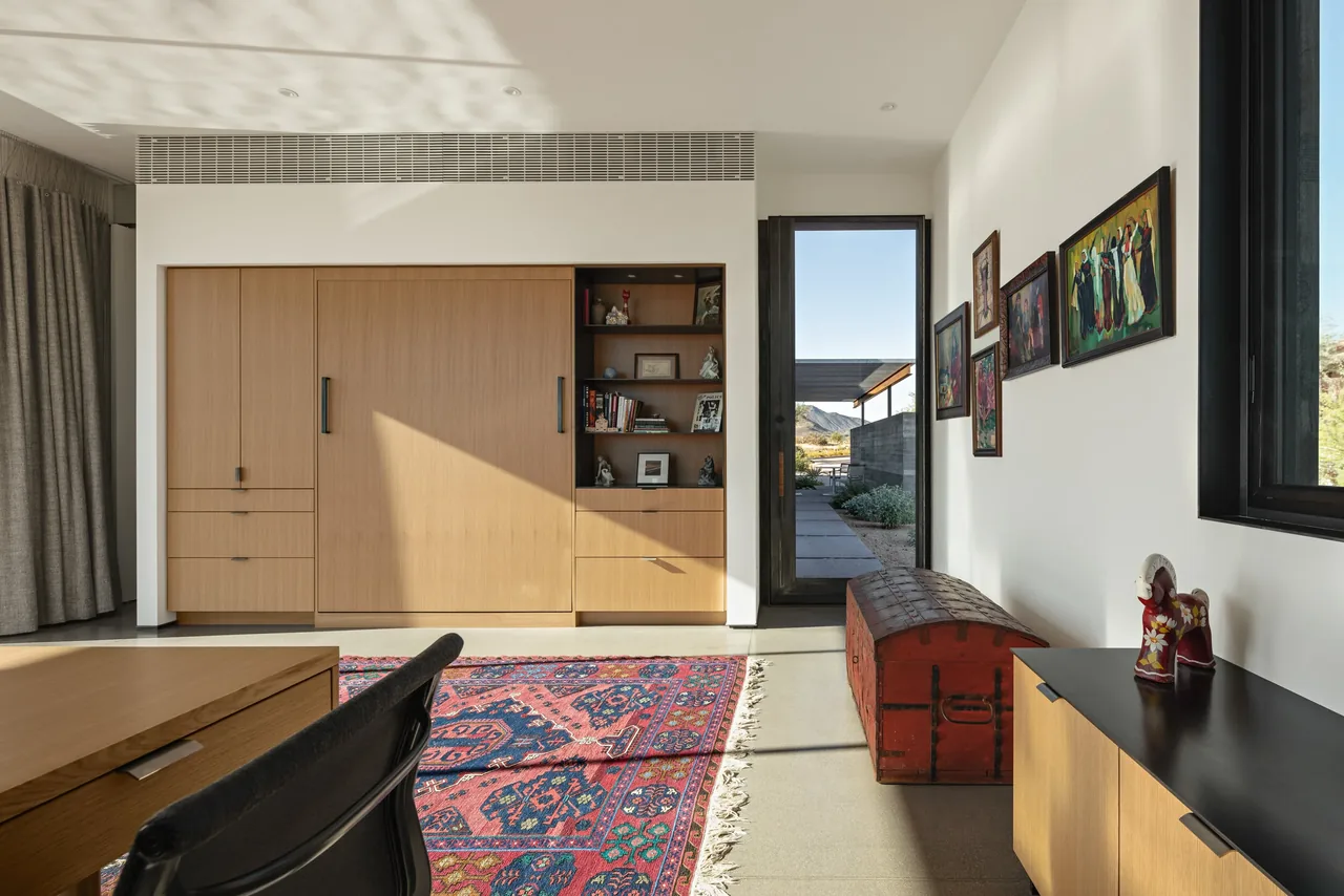 Room with built-in cabinetry, colorful patterned rug, and desert landscape visible through door.