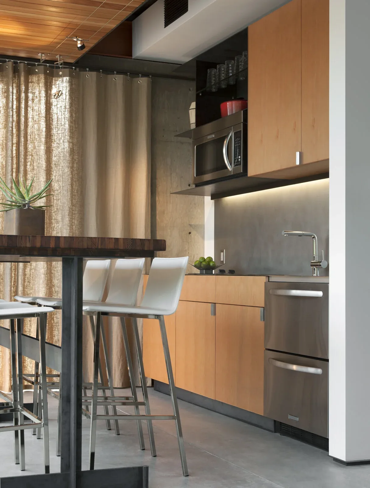 Kitchen space featuring light wood cabinetry, stainless steel dishwasher and microwave, and a wood ceiling above.