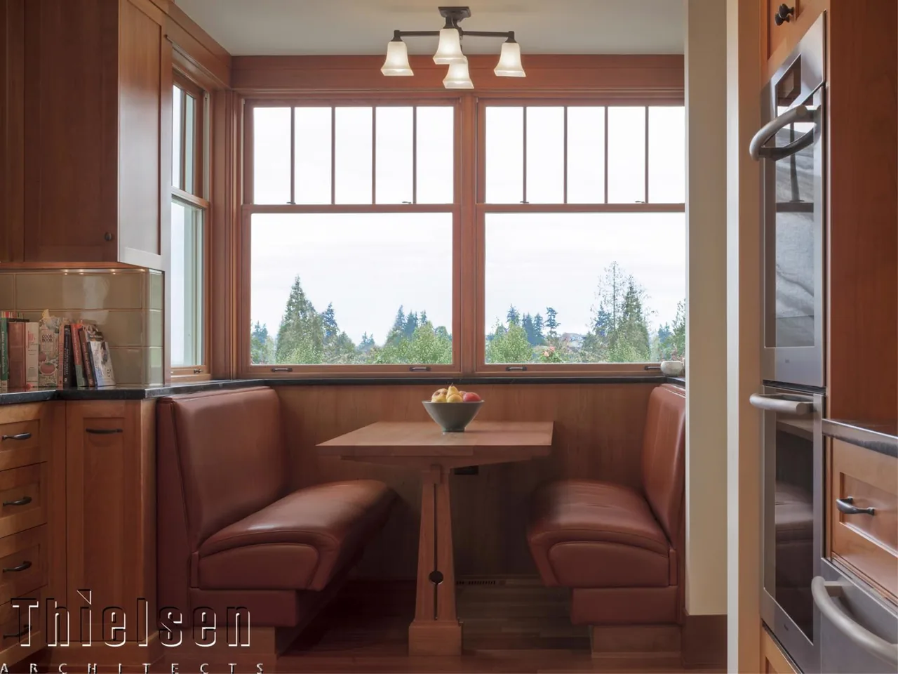 Built-in leather booth seating in the kitchen nook with multi-pane windows framing an outdoor view.